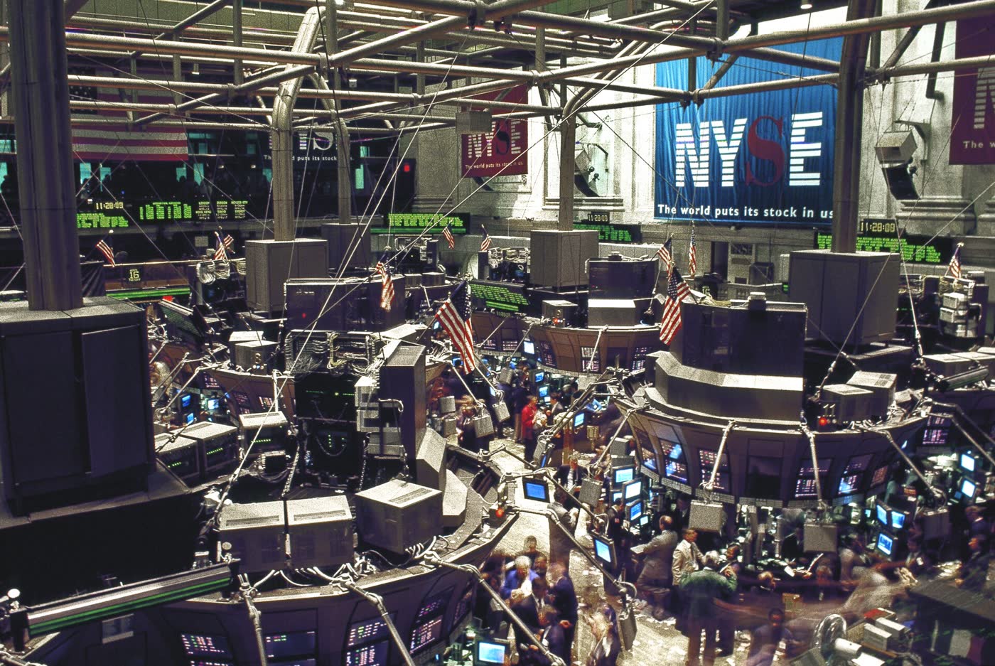 A crowded electronic trading floor with screens and booths